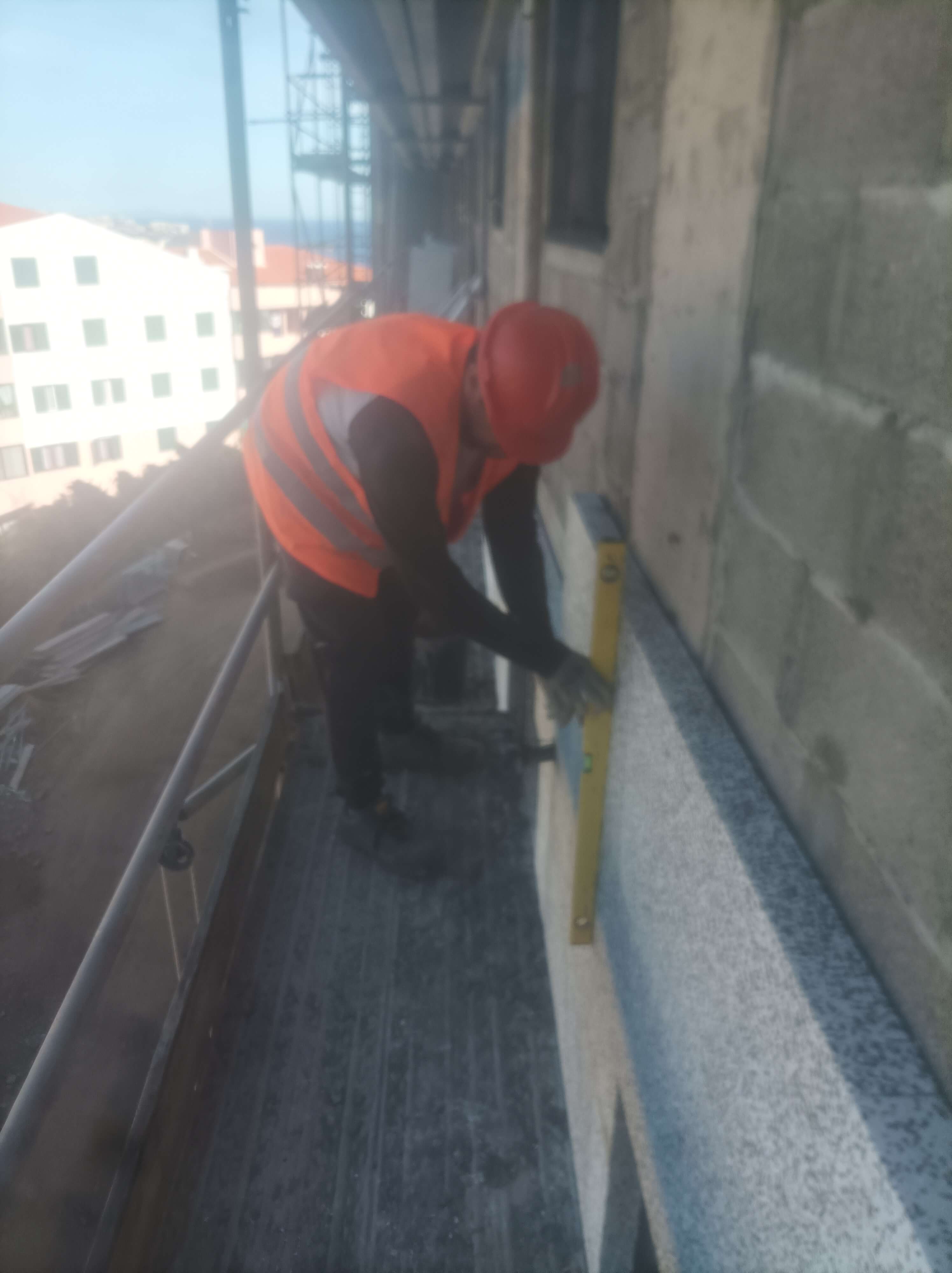 Trabalhador aplicando esferovix na parede do predio